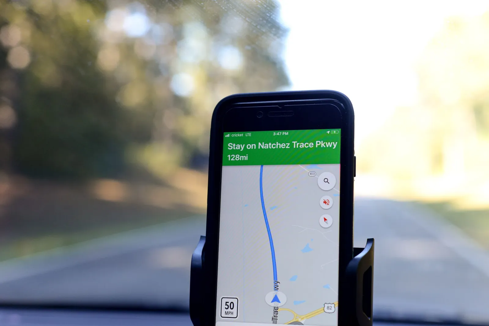 A smartphone mounted on a car dashboard displaying turn-by-turn map navigation