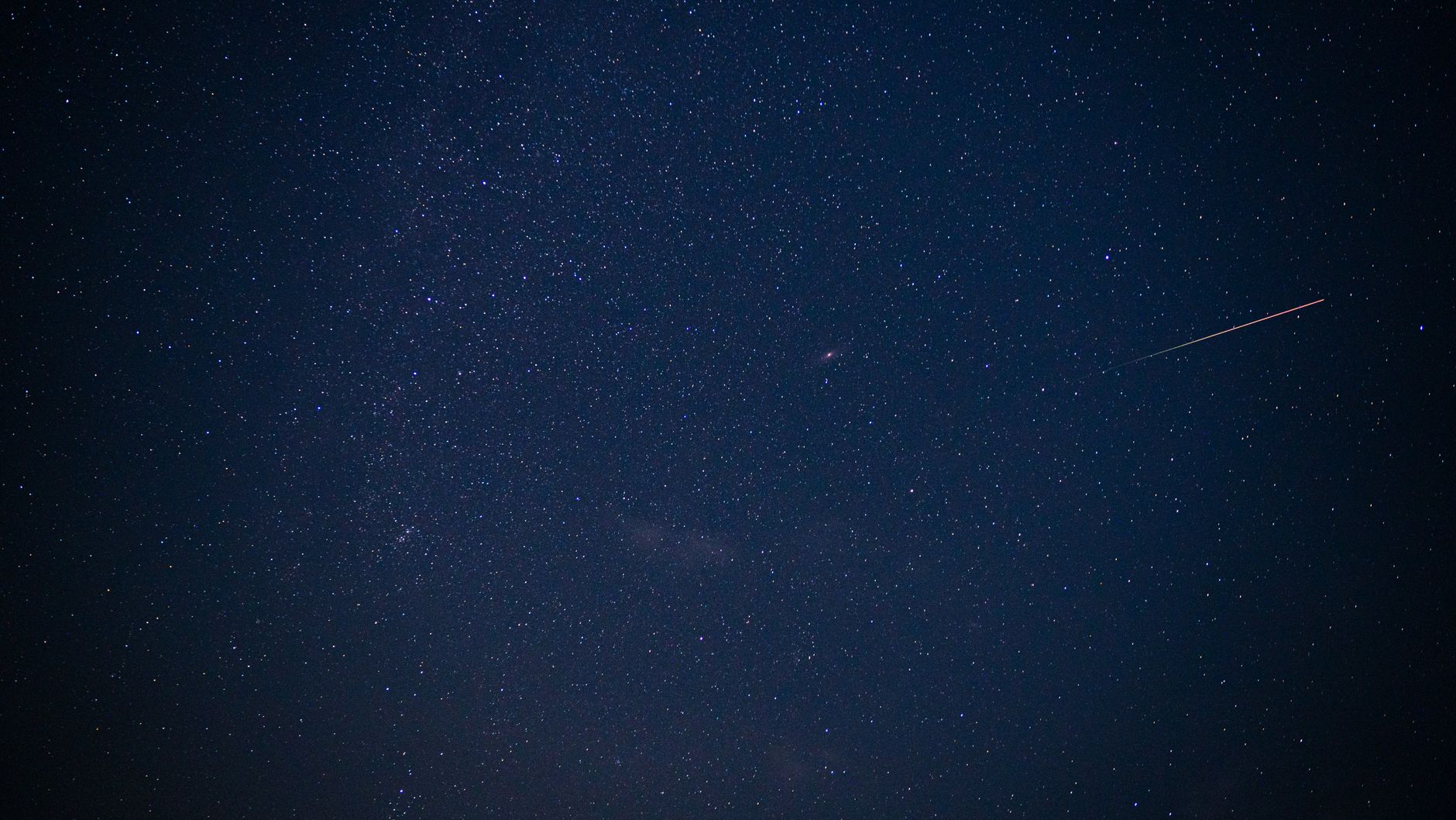 Serene night sky filled with stars and a streaking meteor, showcasing cosmic beauty.