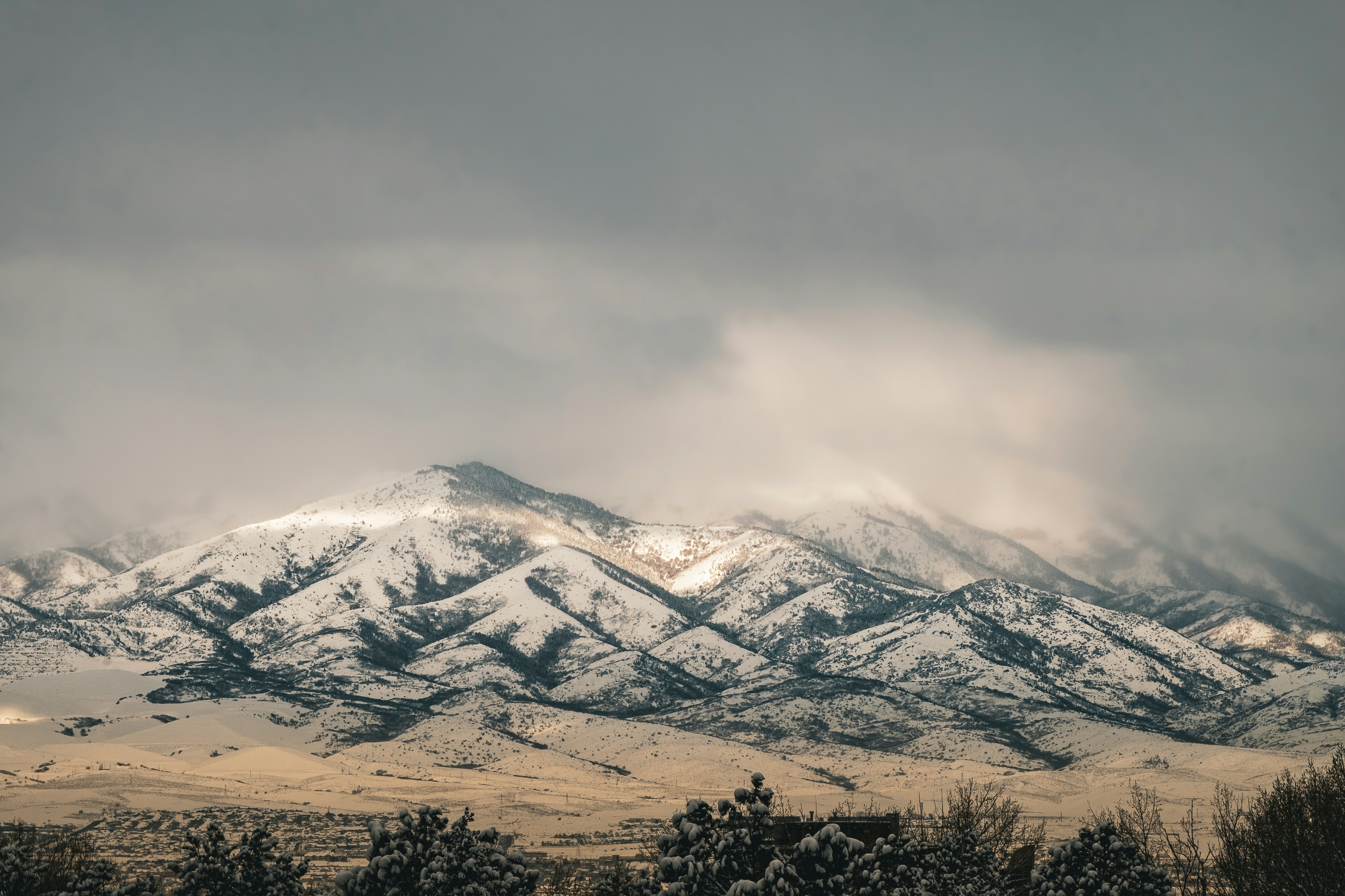 a snow covered mountain range under a cloudy sky